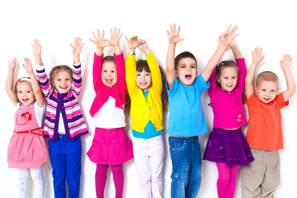 large group of children happily pulled his hands up in  white wall